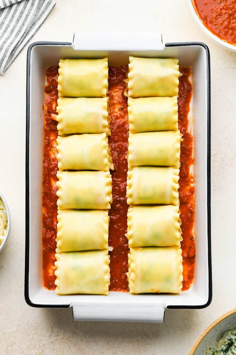 Lasagna rolls in a white pan on marinara sauce