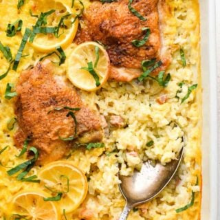 A classic lemon chicken and rice casserole ready to serve with a spoon scooping out rice