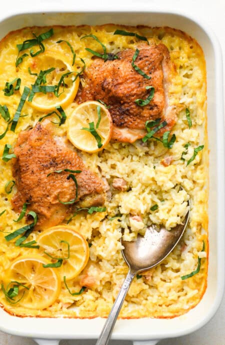 A classic lemon chicken and rice casserole ready to serve with a spoon scooping out rice