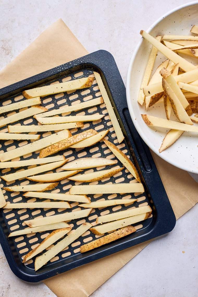 Potato wedges on an air fryer pan before cooking