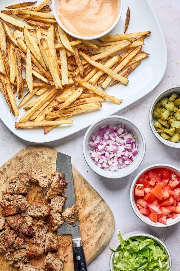 Fries, cut up burger meat, and garnishes for making a recipe