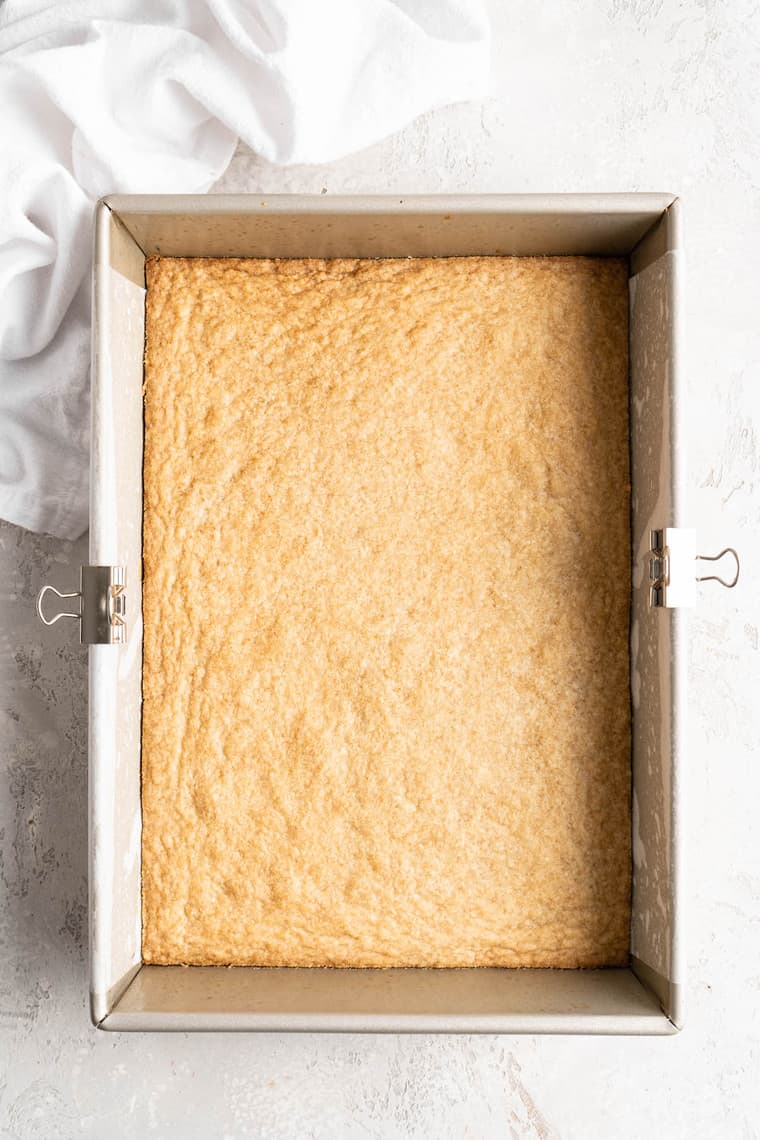A baking pan filled with a shortbread crust after a quick bake