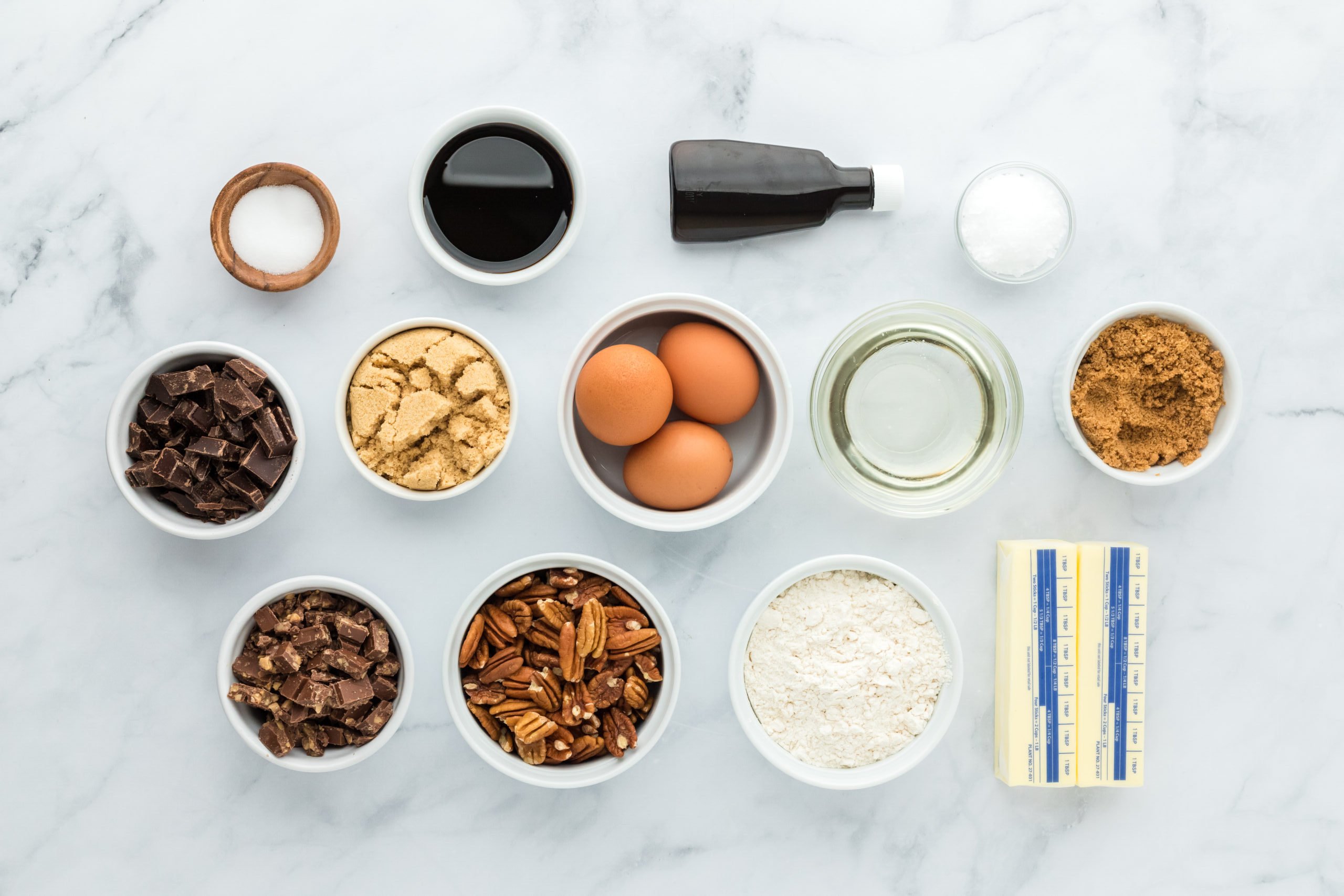 Ingredients to make pecan pie bars recipe in white bowls on white background