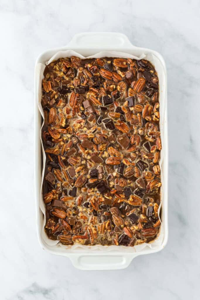 Pecan pie bars filling on top of cookie crust before baking