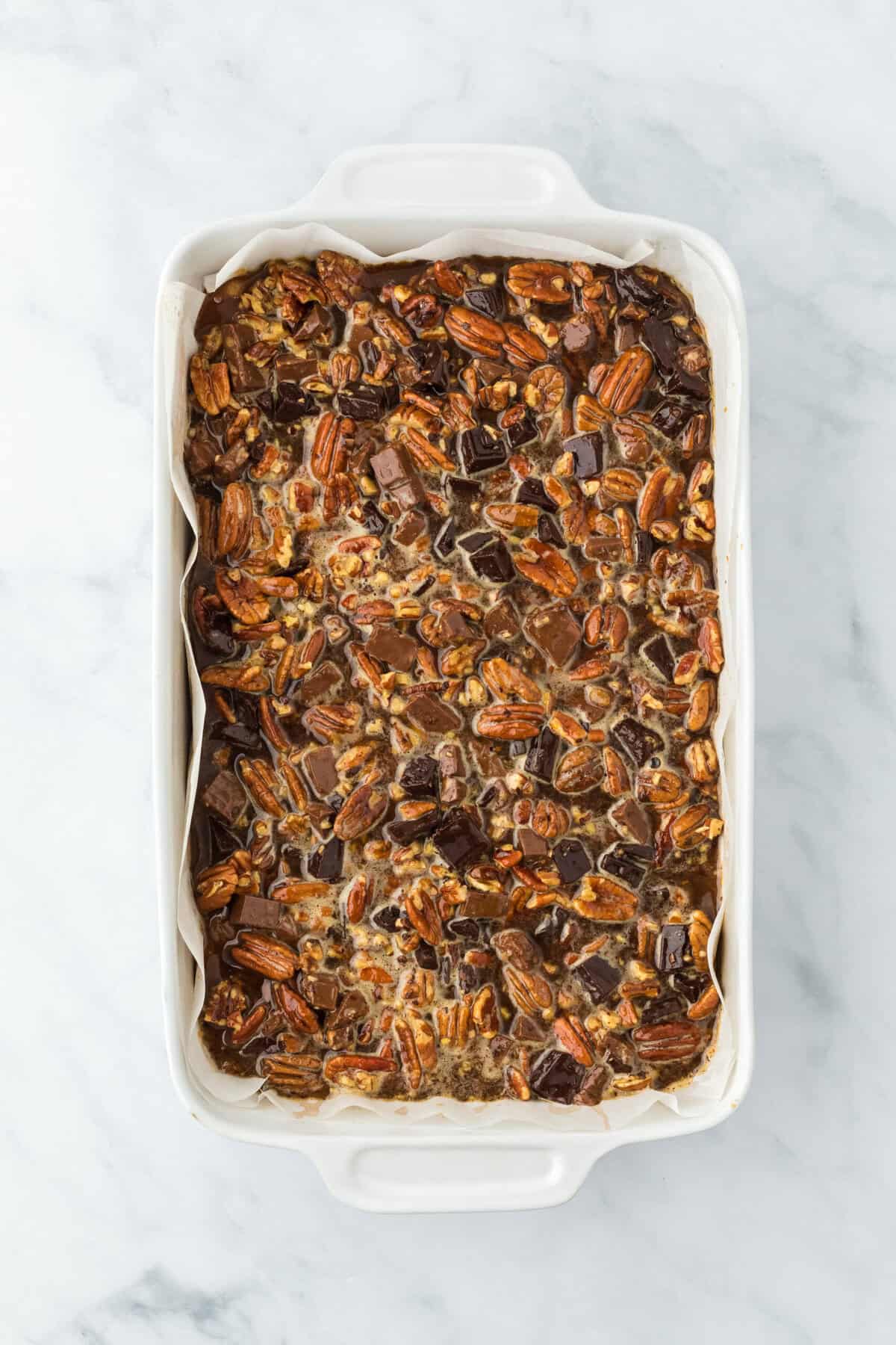 Pecan pie bars filling on top of cookie crust before baking