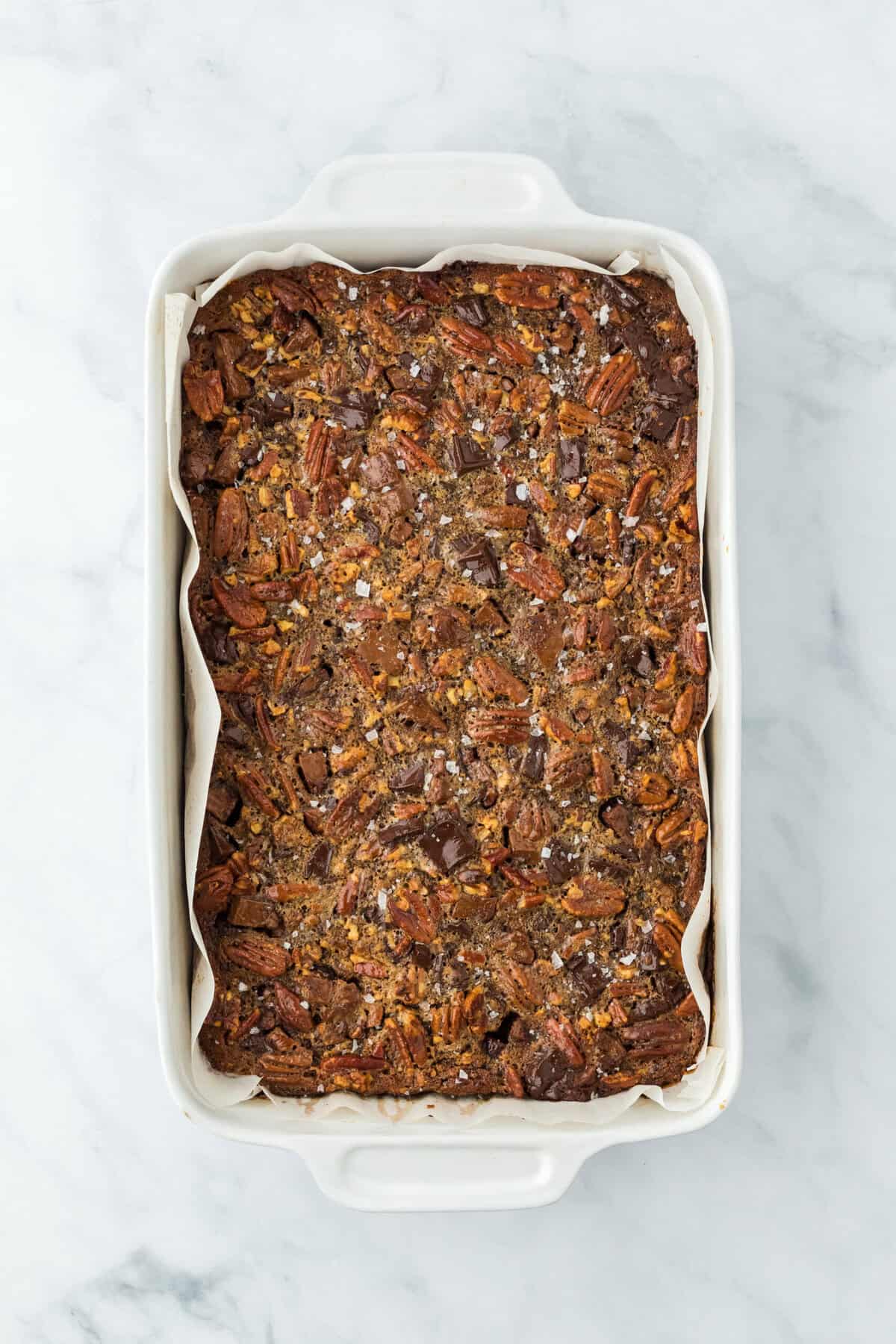 Baked pecan bar recipe in white baking pan on a white background