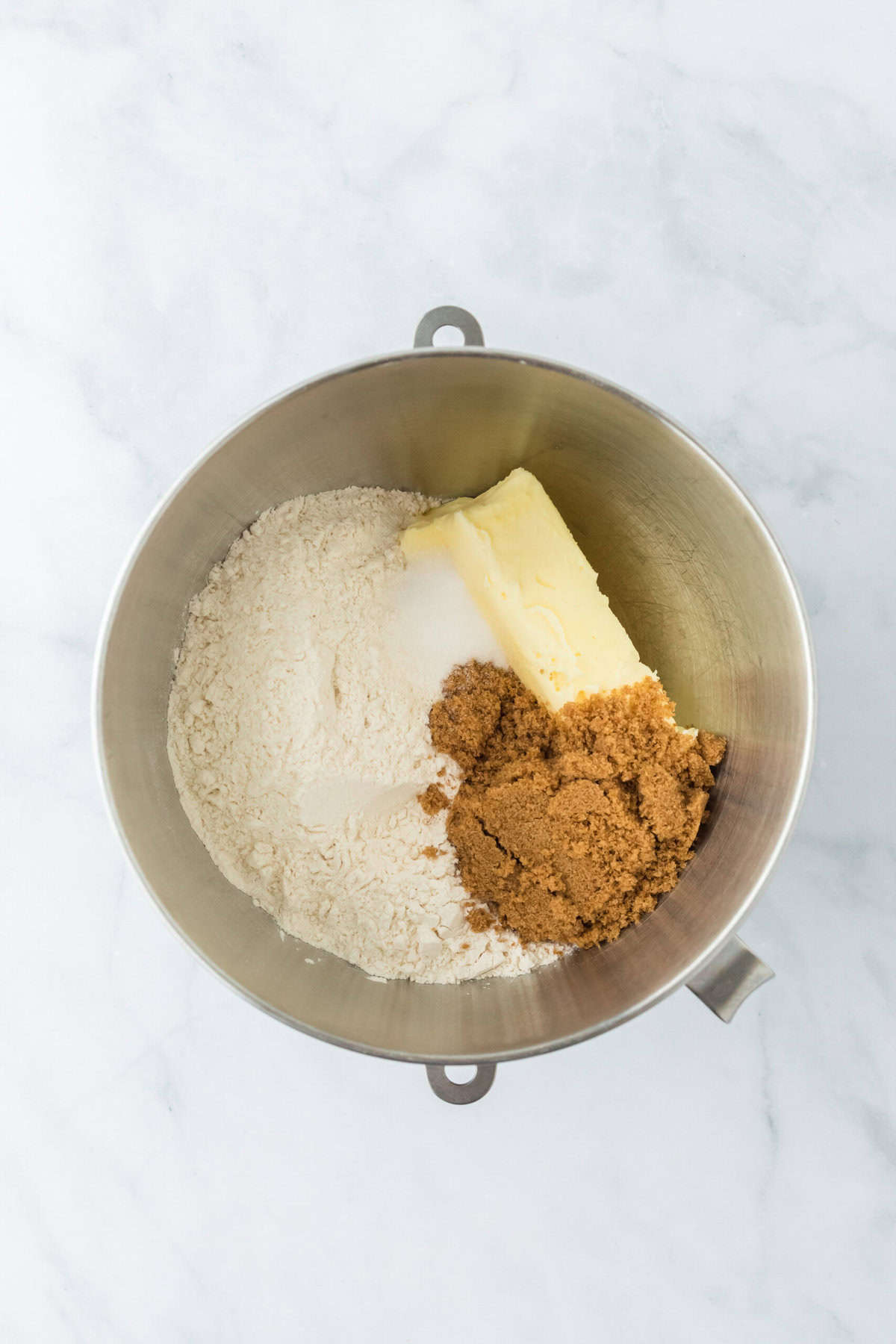 Butter, sugar, flour and salt added to a stand mixer on white background