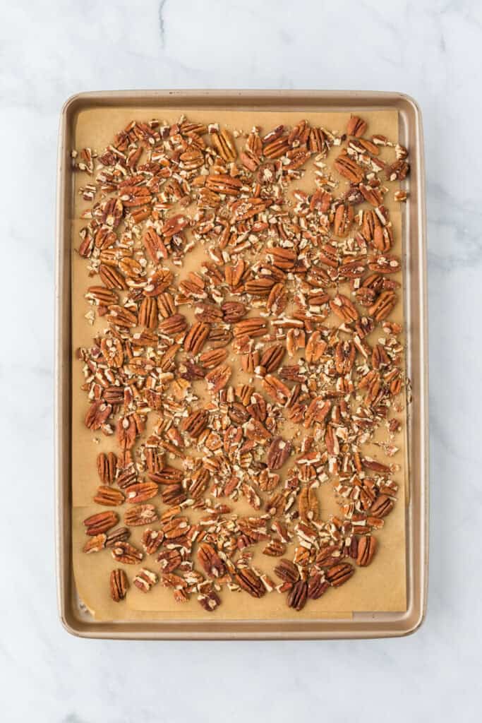 Toasted pecans on a parchment lined baking sheet