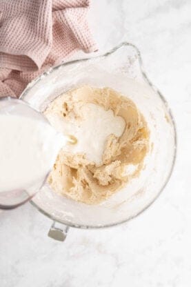 Milk pouring into cake batter in a mixing bowl