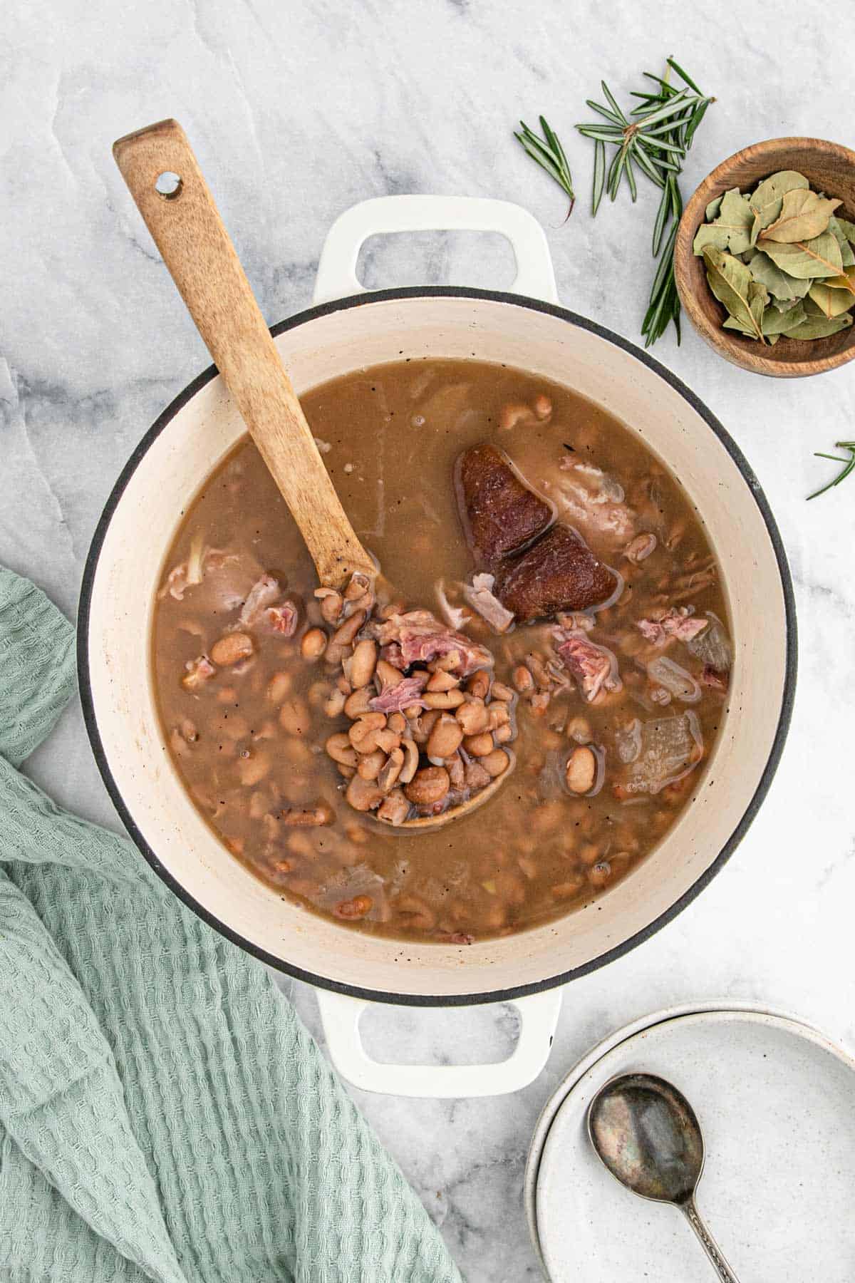 A pot of pinto beans on the table with a spoon lifting some up from the broth.
