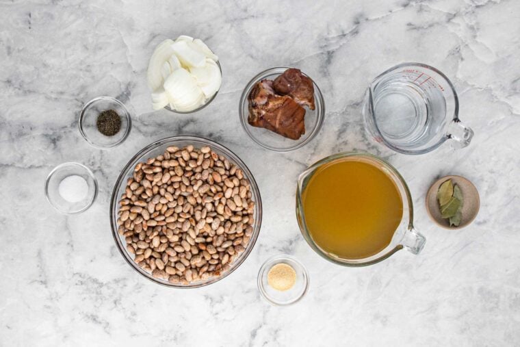 Ingredients in a pinto bean recipe on a marble countertop.