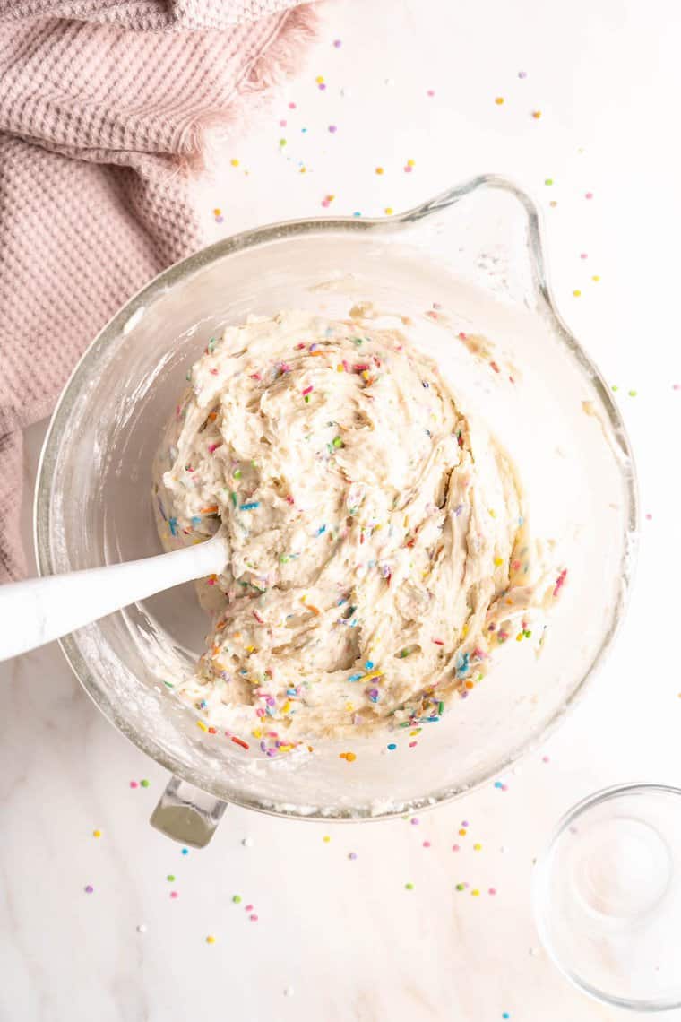 Funfetti cake batter being stirred in a clear bowl