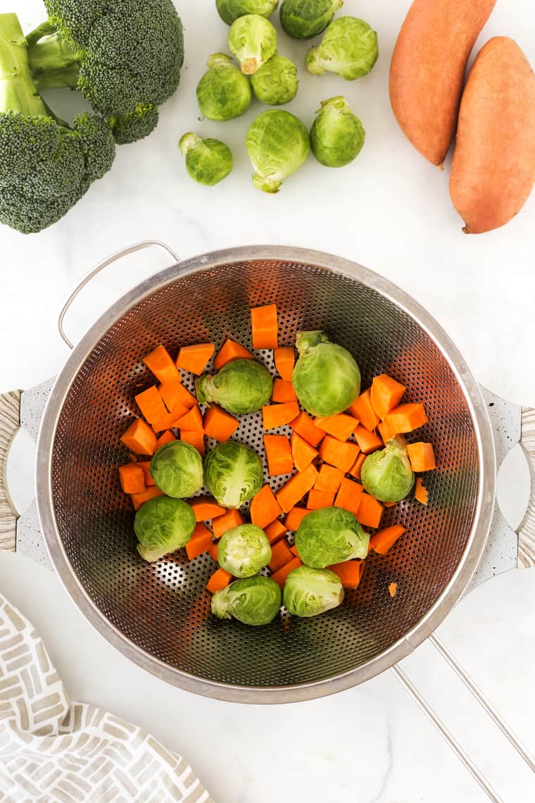 An overhead of carrots and broccoli in a colinder