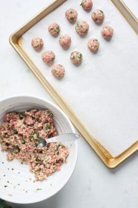 Meatballs being lined on a baking sheet 
