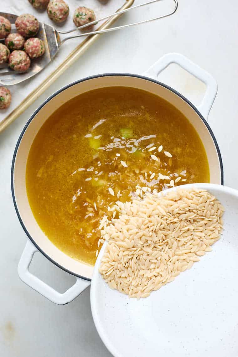 Broth in a dutch oven with rice being added in