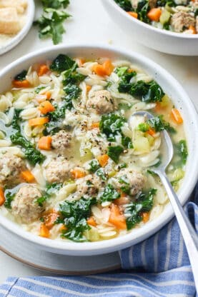 A close up of a bowl with a spoon of Italian Wedding Soup ready to serve