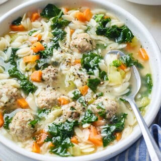 A close up of a bowl with a spoon of Italian Wedding Soup ready to serve