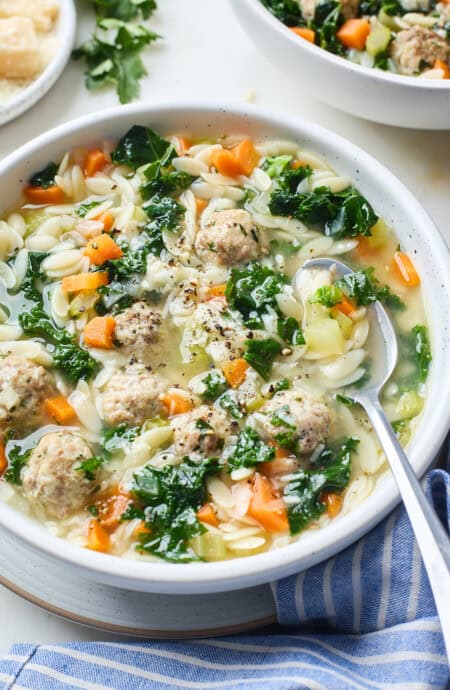 A close up of a bowl with a spoon of Italian Wedding Soup ready to serve