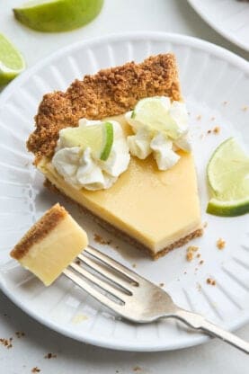 A slice of classic key lime pie being eaten on a white plate
