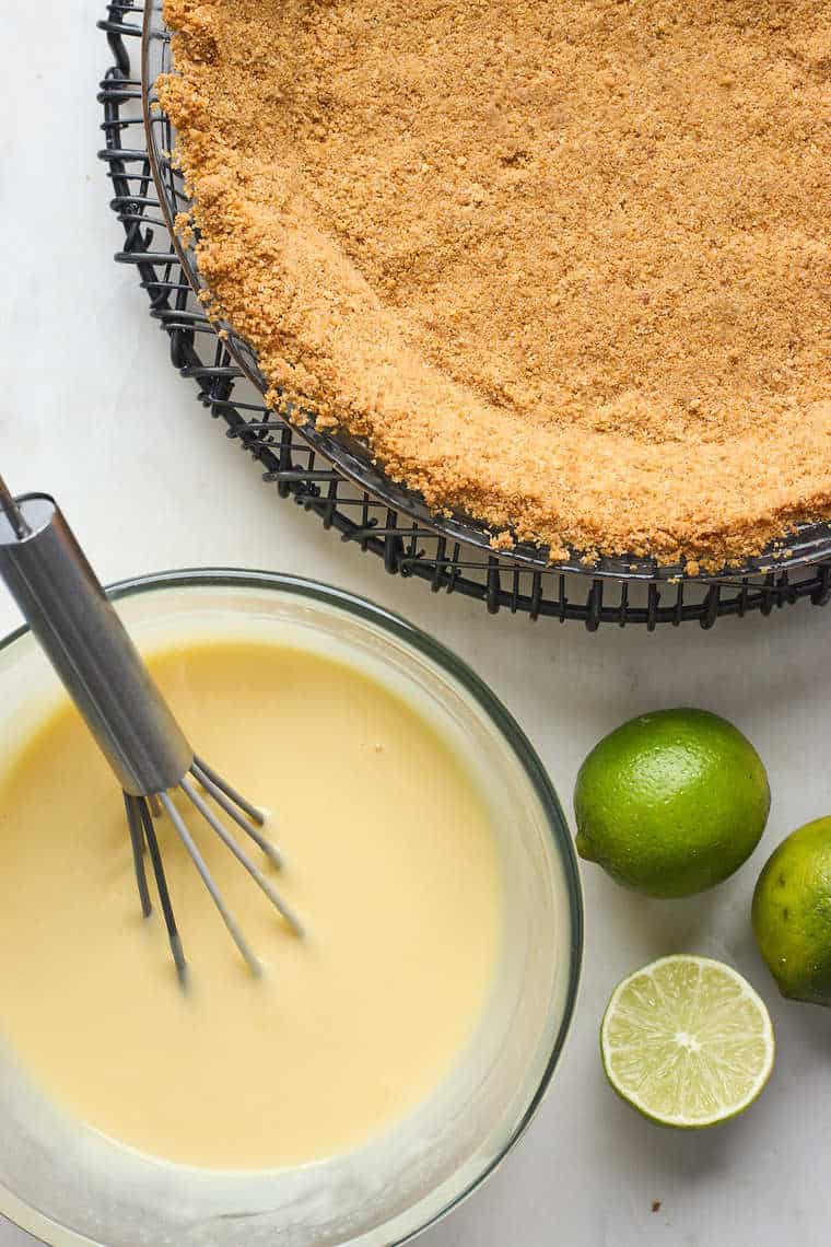 Key lime custard in a clear bowl and a graham cracker crust nearby