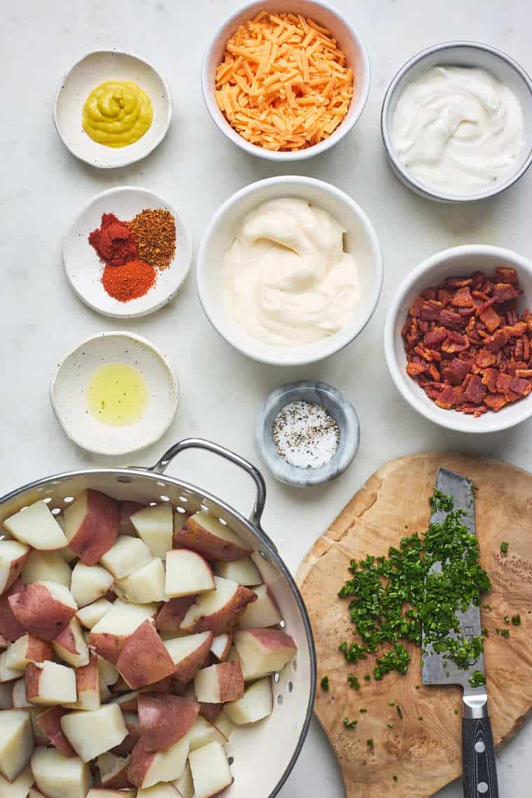 An overhead of potatoes, chives, bacon, seasonings and sour cream ready to put together