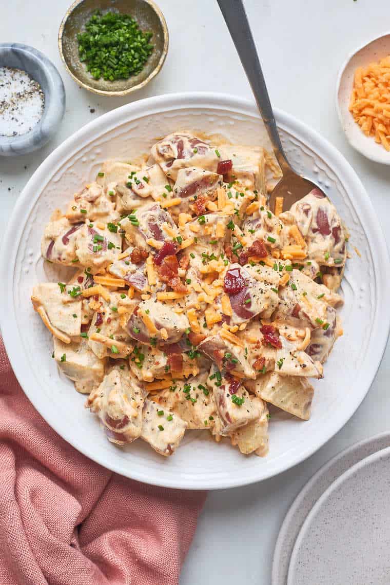 A baked potato salad being stirred together before serving