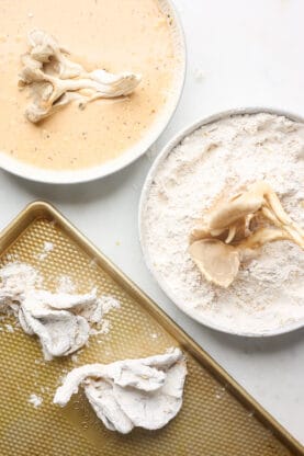 Vegan chicken being dredged in seasoned flour and milk mixture