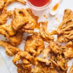 Vegan fried chicken pieces on a white background with maple syrup sauce drizzled on top