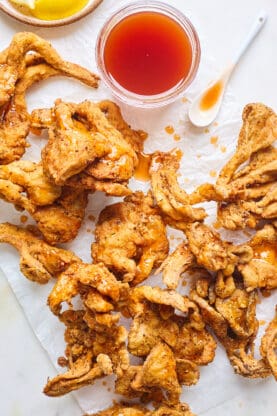 Vegan fried chicken pieces on a white background with maple syrup sauce drizzled on top