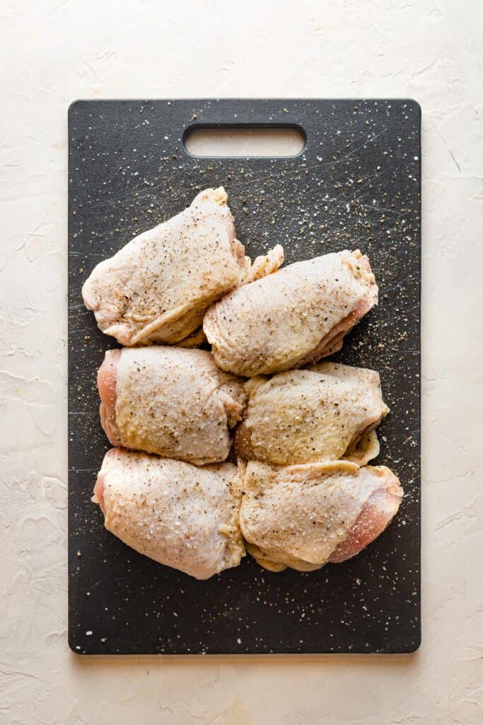 Seasoned chicken thighs on a black board