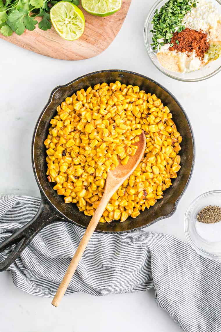 Corn kernels being cooked in a cast iron skillet