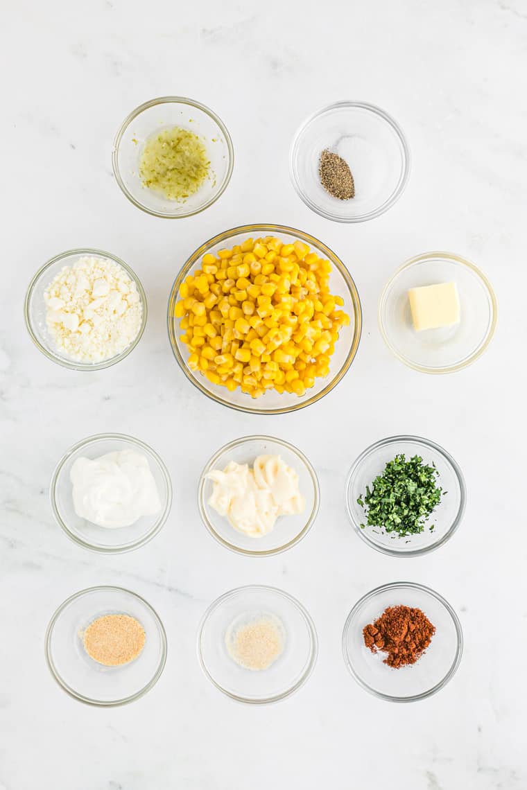Corn, cheese, spices and cilantro in clear bowls before combining into a dip