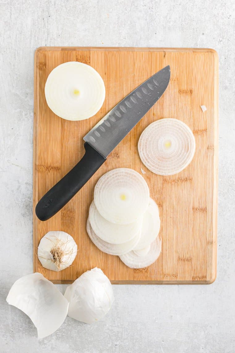 White onions cut into rings on a wooden cutting board