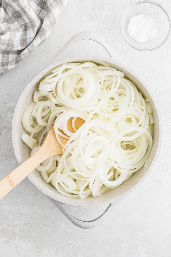 Onion rings being stirred together in a skillet
