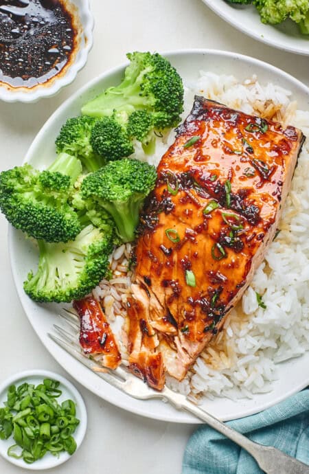A honey garlic salmon filet being eaten with white rice and broccoli
