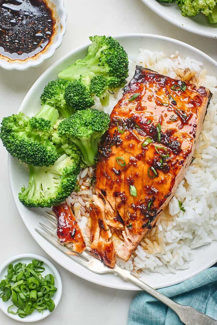 A honey garlic salmon filet being eaten with white rice and broccoli