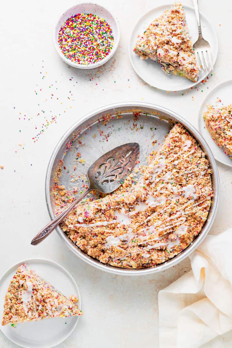 A delicious funfetti coffee cake on a white background with slices removed