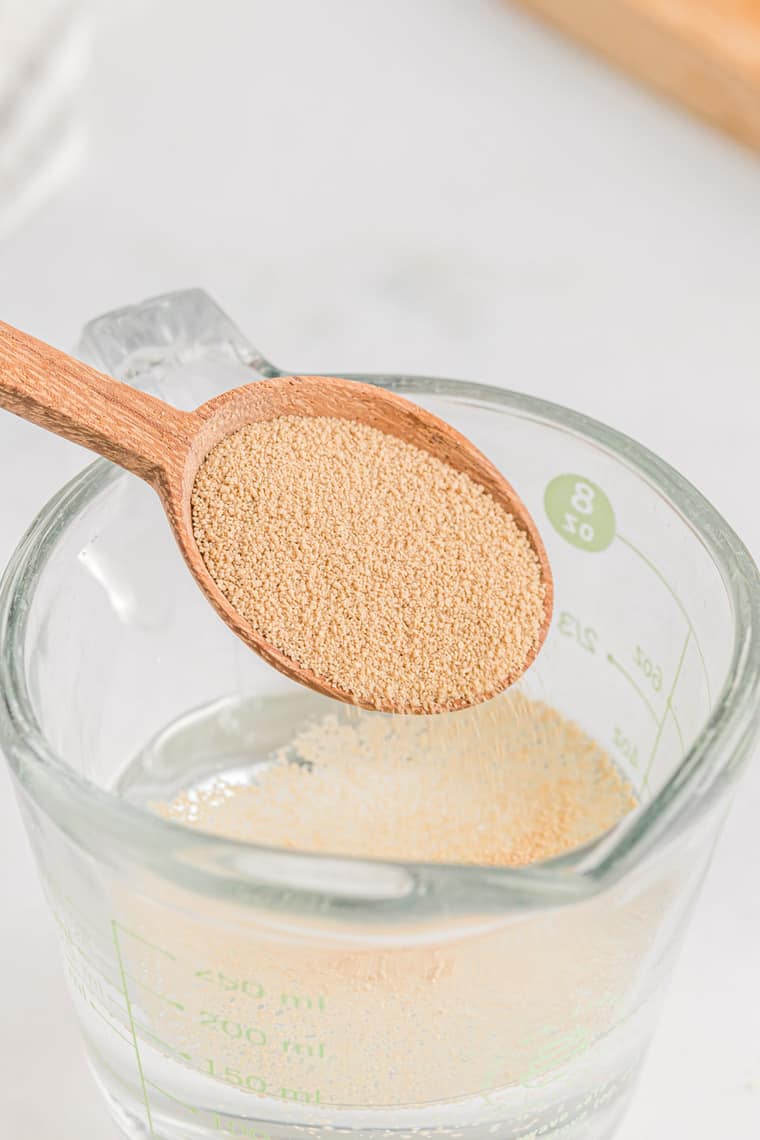 Active yeast being added to a measuring cup filled with water