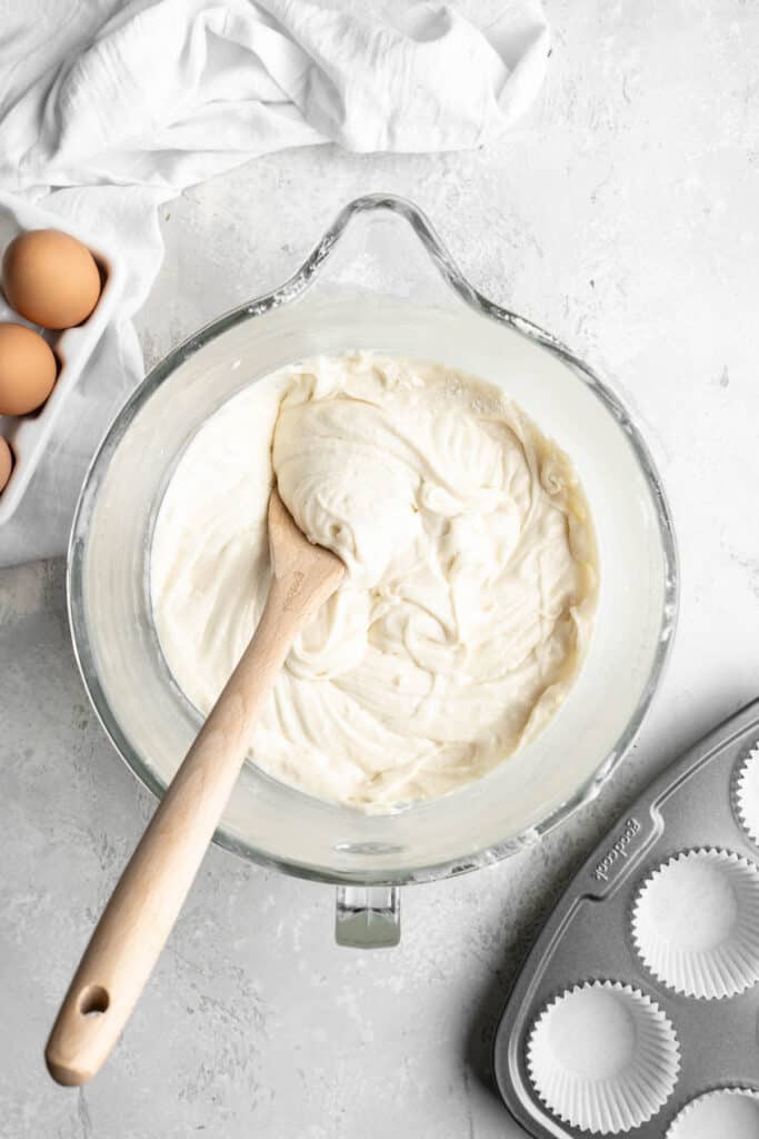Lemon cupcake batter in a mixing bowl with a wooden spoon stirring it