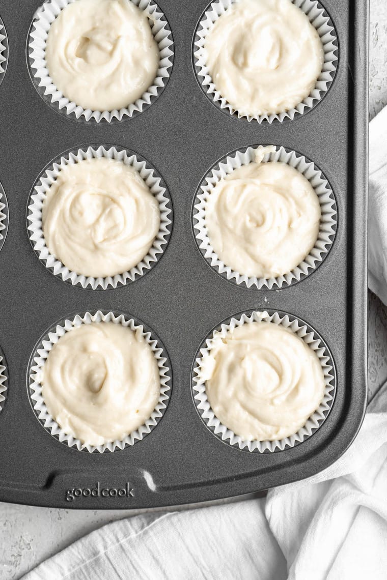 A close up of a muffin pan filled with lemon cupcake batter in tins before baking