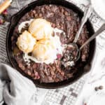 An overhead of a skillet brownie with three scoops of vanilla ice cream melting on top