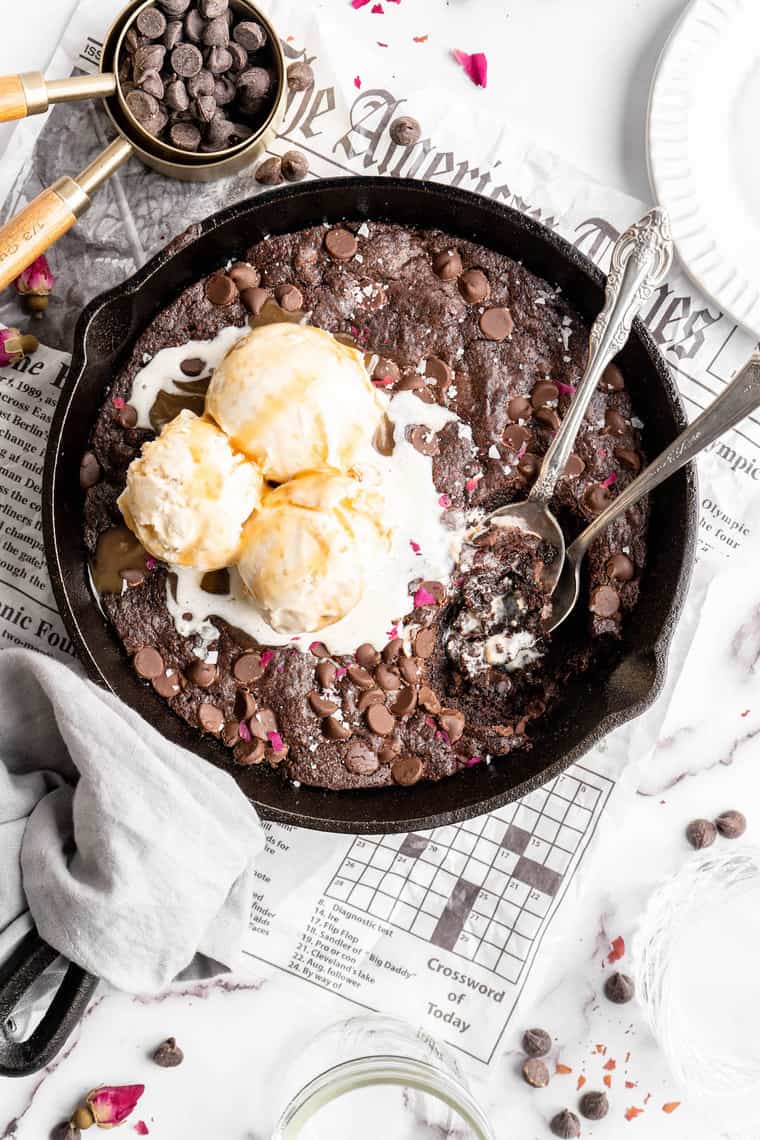 An overhead of a skillet brownie with three scoops of vanilla ice cream melting on top