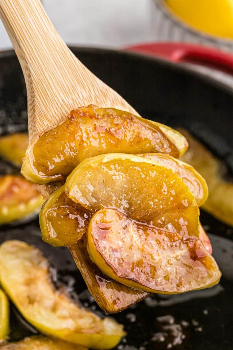 A spatula lifting fried apples after being cooked from a skillet
