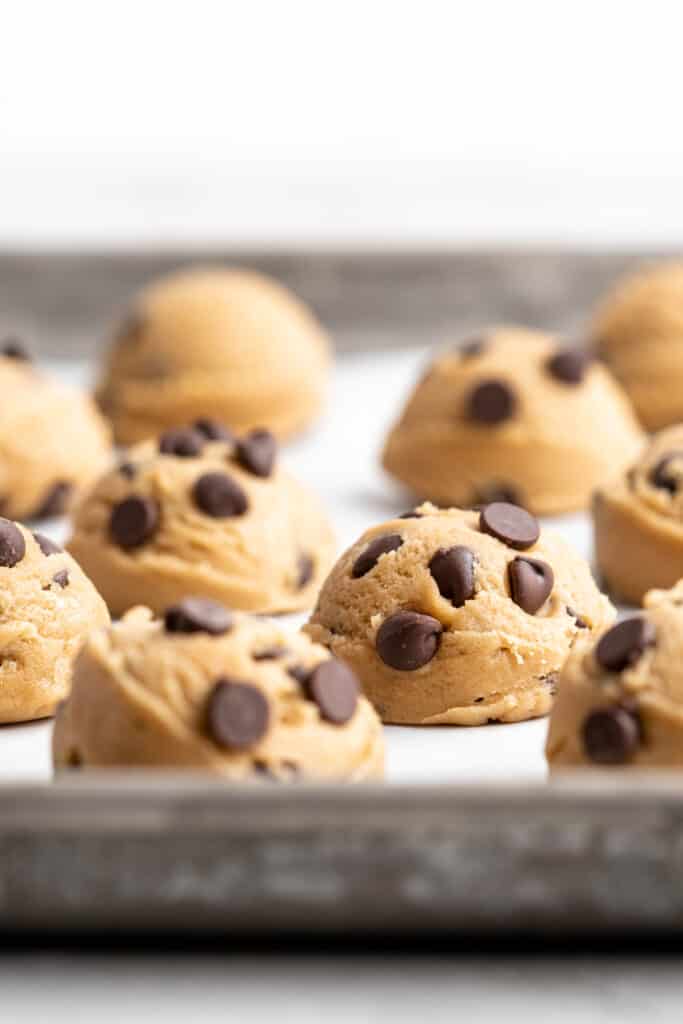 Cookie scoops on a parchment lined baking sheet before baking