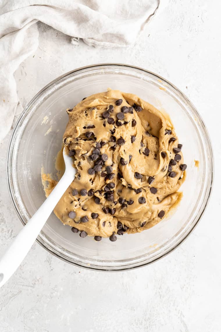 A cookie dough after being folded with chocolate chips in a clear bowl