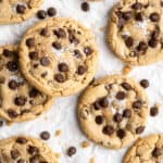 A close up of brown butter chocolate chip cookies scattered on a white background