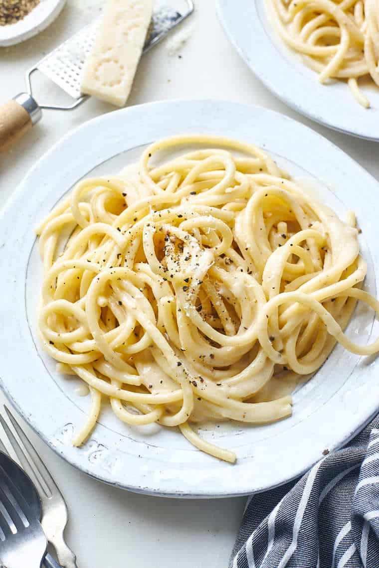 A close up of two white plates with pasta ready to serve