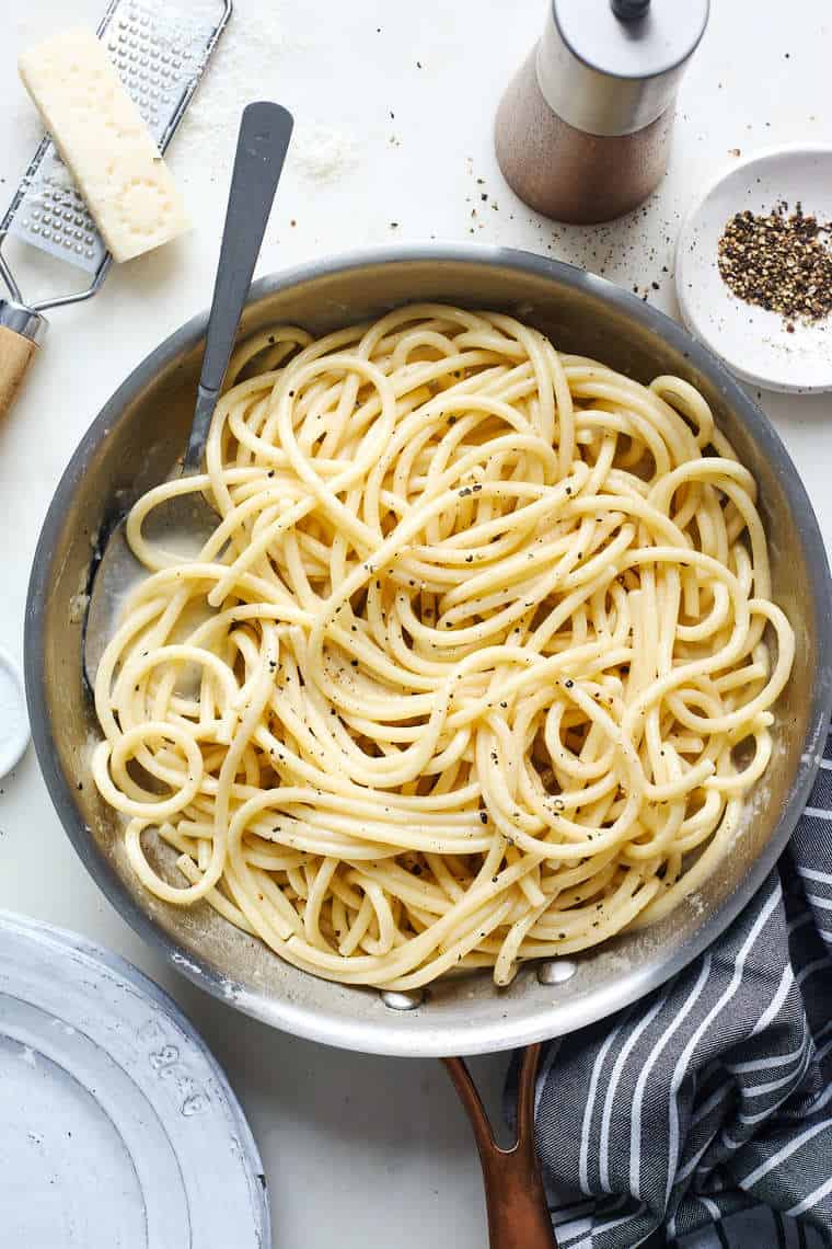 Cacio e pepe in a large skillet with butter nearby