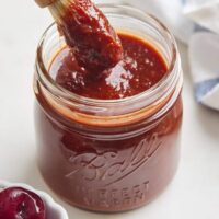 A delicious thick bbq sauce in a mason jar with a brush inside ready to serve