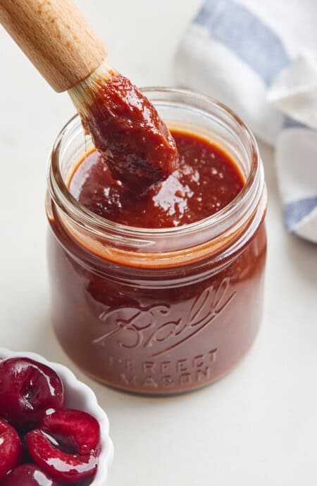 A delicious thick bbq sauce in a mason jar with a brush inside ready to serve